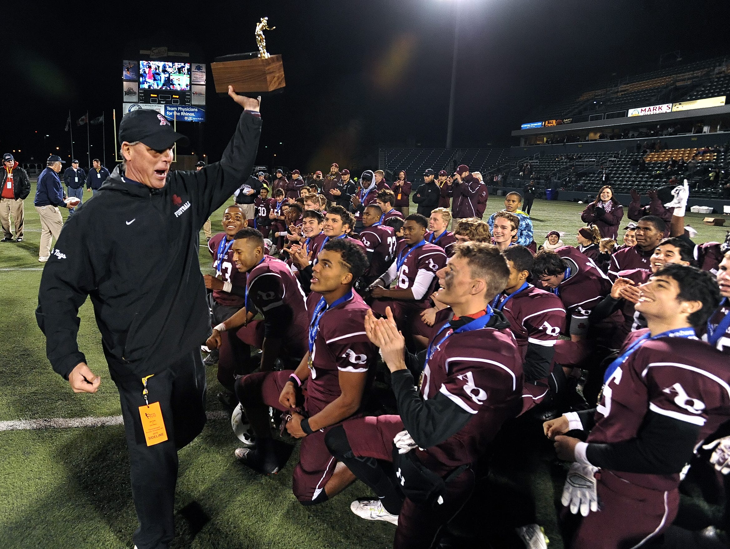 Aquinas head coach Chris Battaglia brings the Section V Class AA championship trophy to his players earlier this month at Sahlen's Stadium.