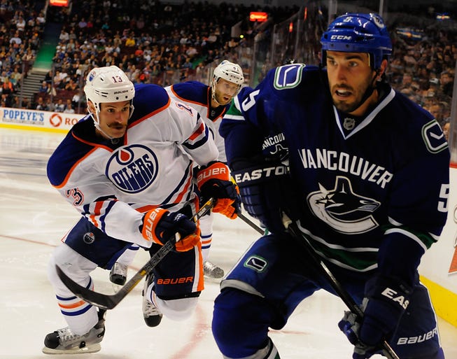 Edmonton Oilers forward Mike Brown and Vancouver Canucks forward Zack Kassian chase a loose puck during the third period at Rogers Arena.
