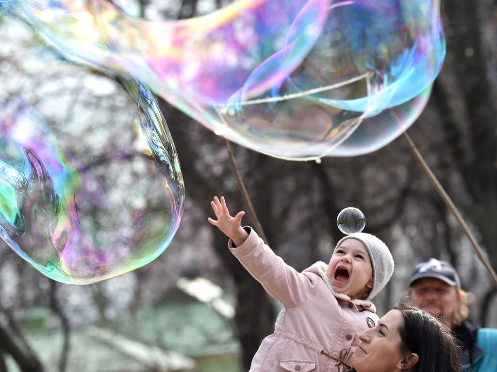 A girl reacts as she reaches for soap bubbles made by a street artist in Kiev, Ukraine.
