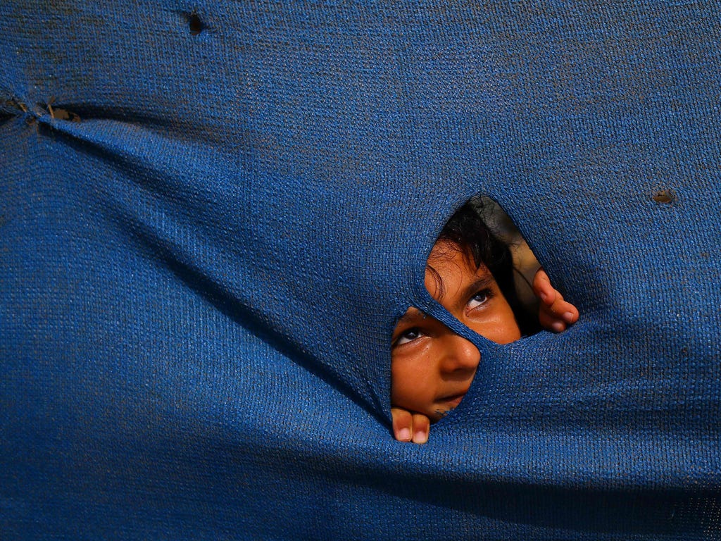 A Palestinian girl peers through a tarp next to her house in Gaza City.