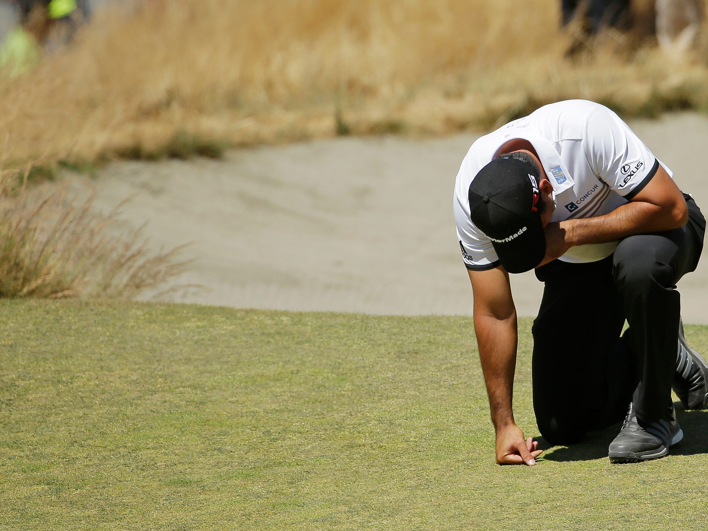 Jason Day, of Australia, kneels while waiting to putt on the ninth hole after having collapsed earlier in the fairway during the second round of the U.S. Open golf tournament at Chambers Bay on Friday, June 19, 2015 in University Place, Wash. (AP Photo/Ted S. Warren)