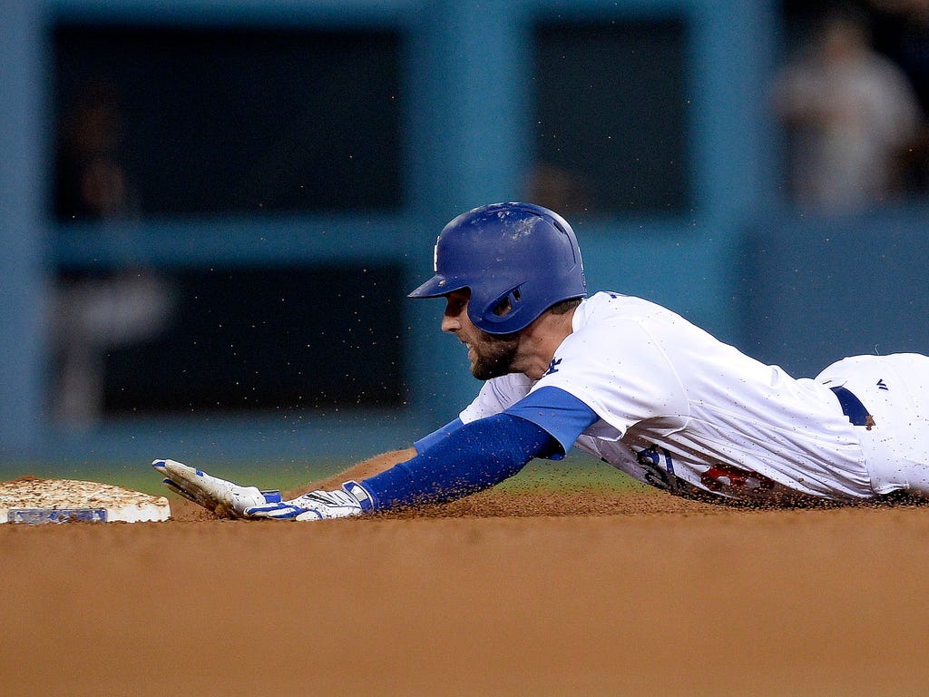Dodgers hitter Chris Taylor slides faely into second base with a double during the seventh inning against the Giants in Los Angeles. Taylor drove in a run with the hit to help the Dodgers win 6-4.