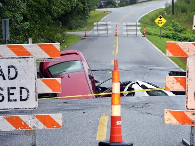 Heavy rains caused the ground to collapse near Tryon St. and Memorial Dr. in Greer late Saturday night. Two cars were still stuck in hole early on Sunday, August 10, 2014.