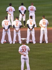 Adam Jones (10) and the Baltimore Orioles stand for