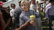 Clinton eats a pork chop on a stick and carries a lemonade