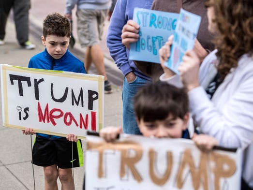 Otis Nix, 8, holds a "Trump is Mean" sign during a