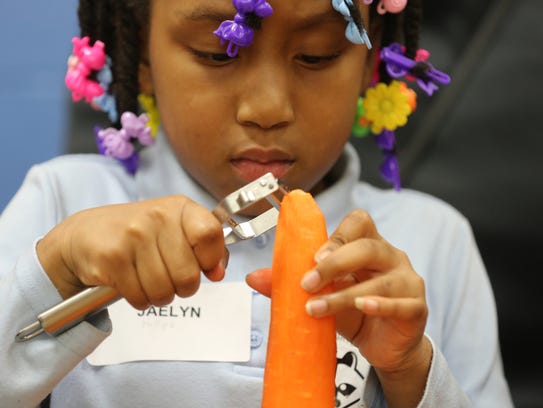 Jaelyn Phillips, 7, peels a carrot in a family cooking