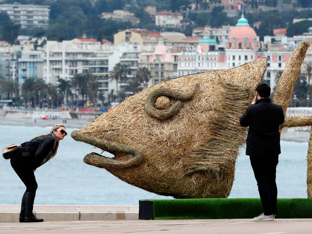 People take pictures of a giant straw fish, created by French sculptor Christian Burger on the French riviera city of Nice during April Fool's Day.