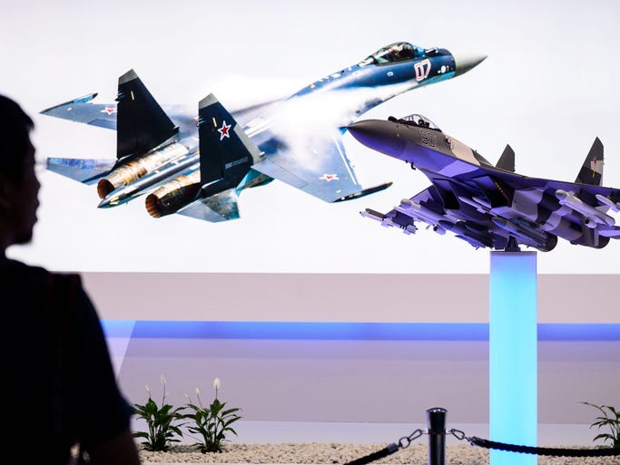 A man walks past a display for the Russian Sukhoi SU-35 jet fighter.