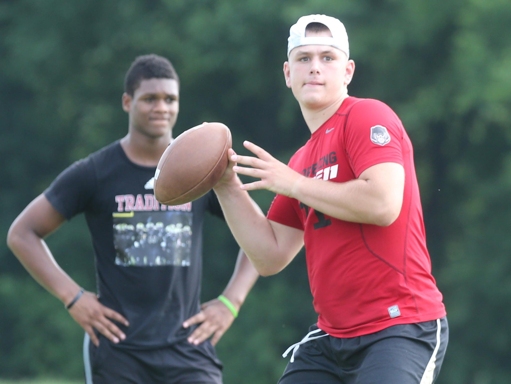 Riverdale quarterback Brandon Bea throws a pass during Monday’s passing practice as teammate Christian Souffront watches. Bea transferred from Washington state.
