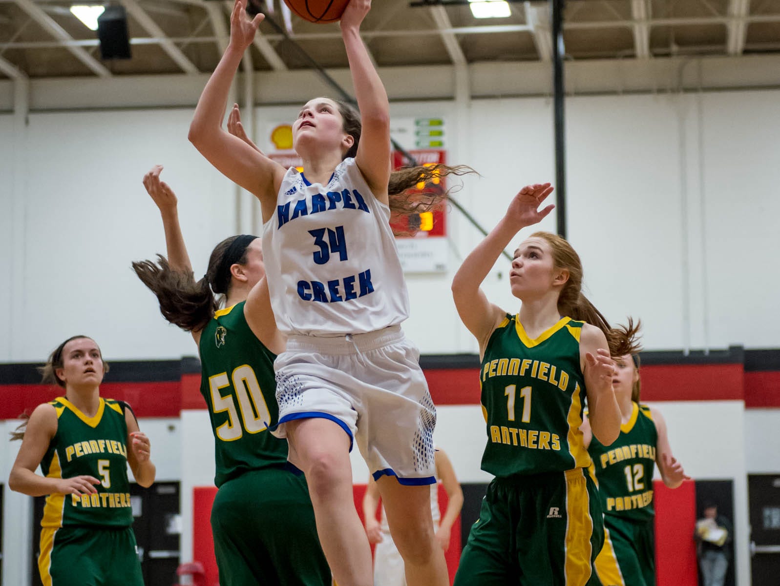 Harper Creek's Faith Hayes (34) goes for the layup over Pennfield defenfers in first round of districts game at Marshall Monday evening.