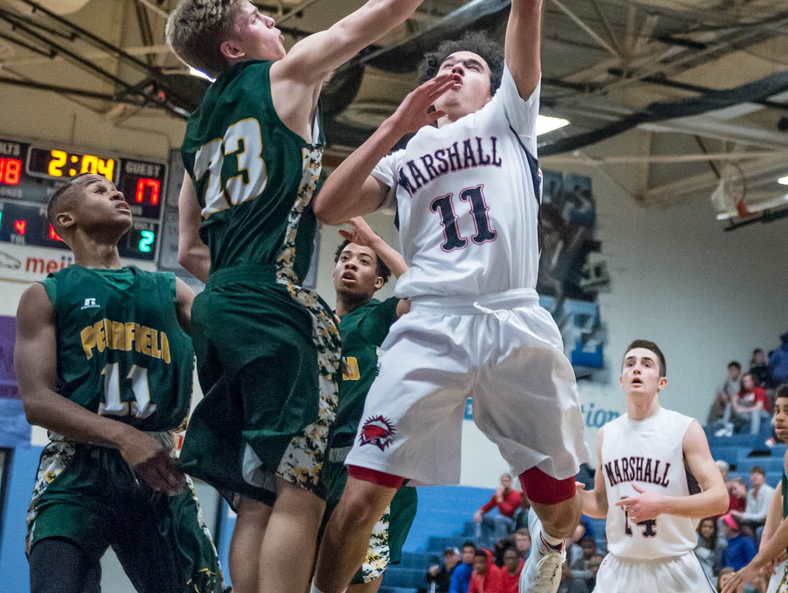 Marshall's Tyler Torrey (11) goes for the hoop while Pennfield's Grant Peterson (23) tries for the block during Monday's district game.