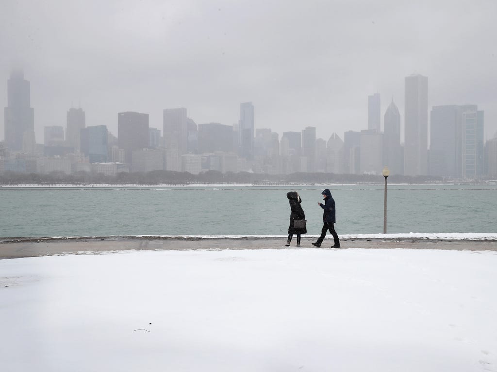People walk along a snow-covered lakefront near downtown Chicago.