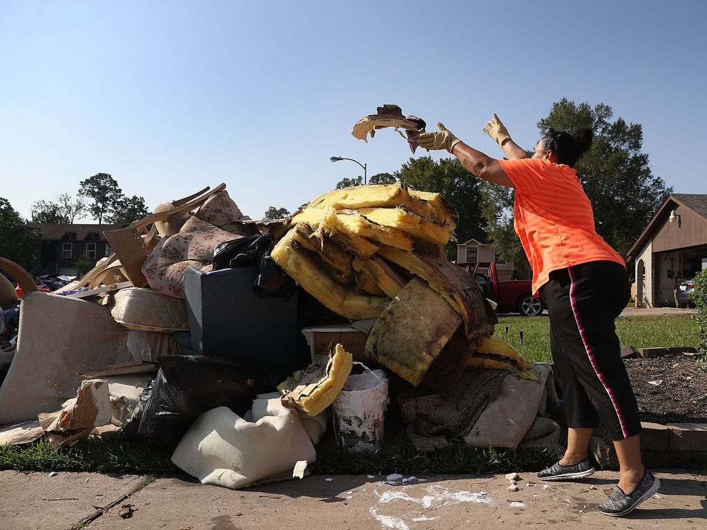 Regina Perry throws out wet sheetrock as she cleans out of her home that was inundated with water as she begins the process of rebuilding after torrential rains caused widespread flooding during Hurricane and Tropical Storm Harvey on Sept. 2, 2017 in