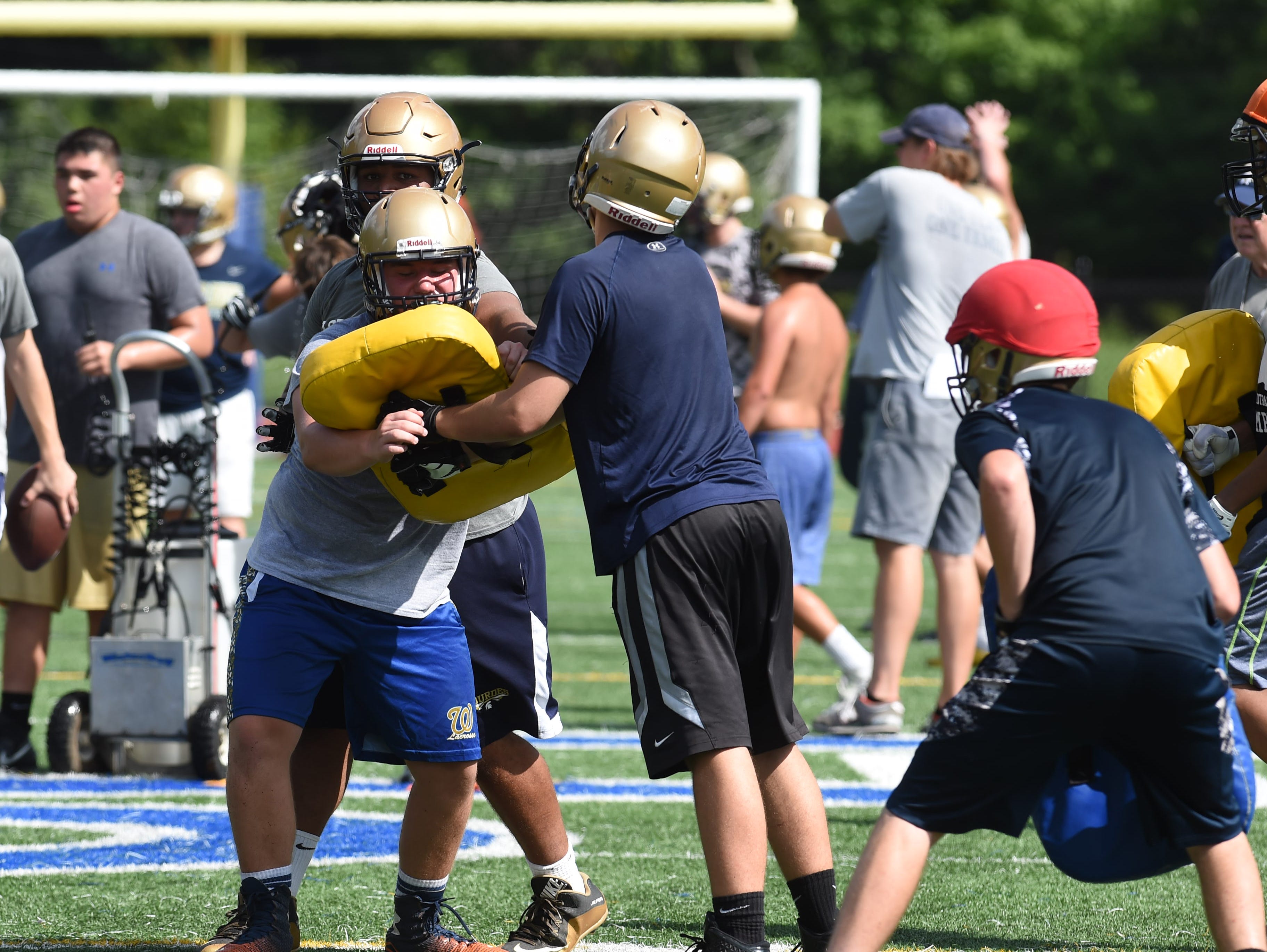 Sophomore Kevin Johansson, left, of Our Lady of Lourdes High School goes for a tackle during preseason football practice.