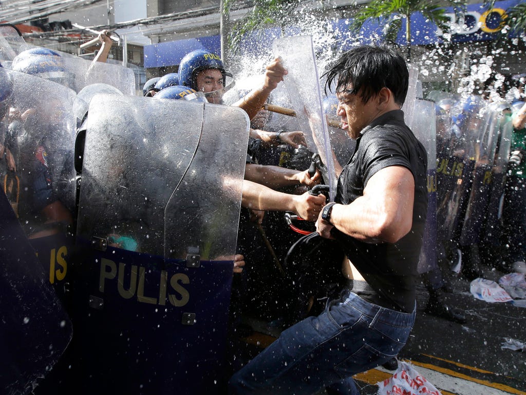 Police try to grab a protester near the U.S. Embassy in Manila, Philippines on Nov. 12, 2017.  Activists rallied against the visit of President Trump, who is currently on a trip to Asia with the Philippines as his last stop for the ASEAN leaders' sum