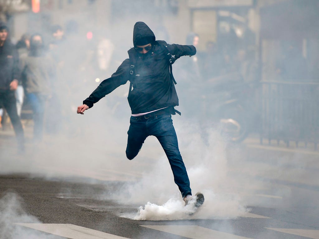A man kicks back a tear gas canister at police in Paris on April 27, 2017, during a demonstration against the results of the first round of the presidential election.
