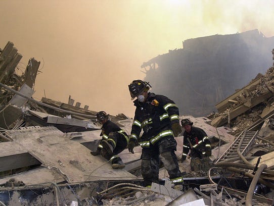 New York City firefighters maneuver around the debris