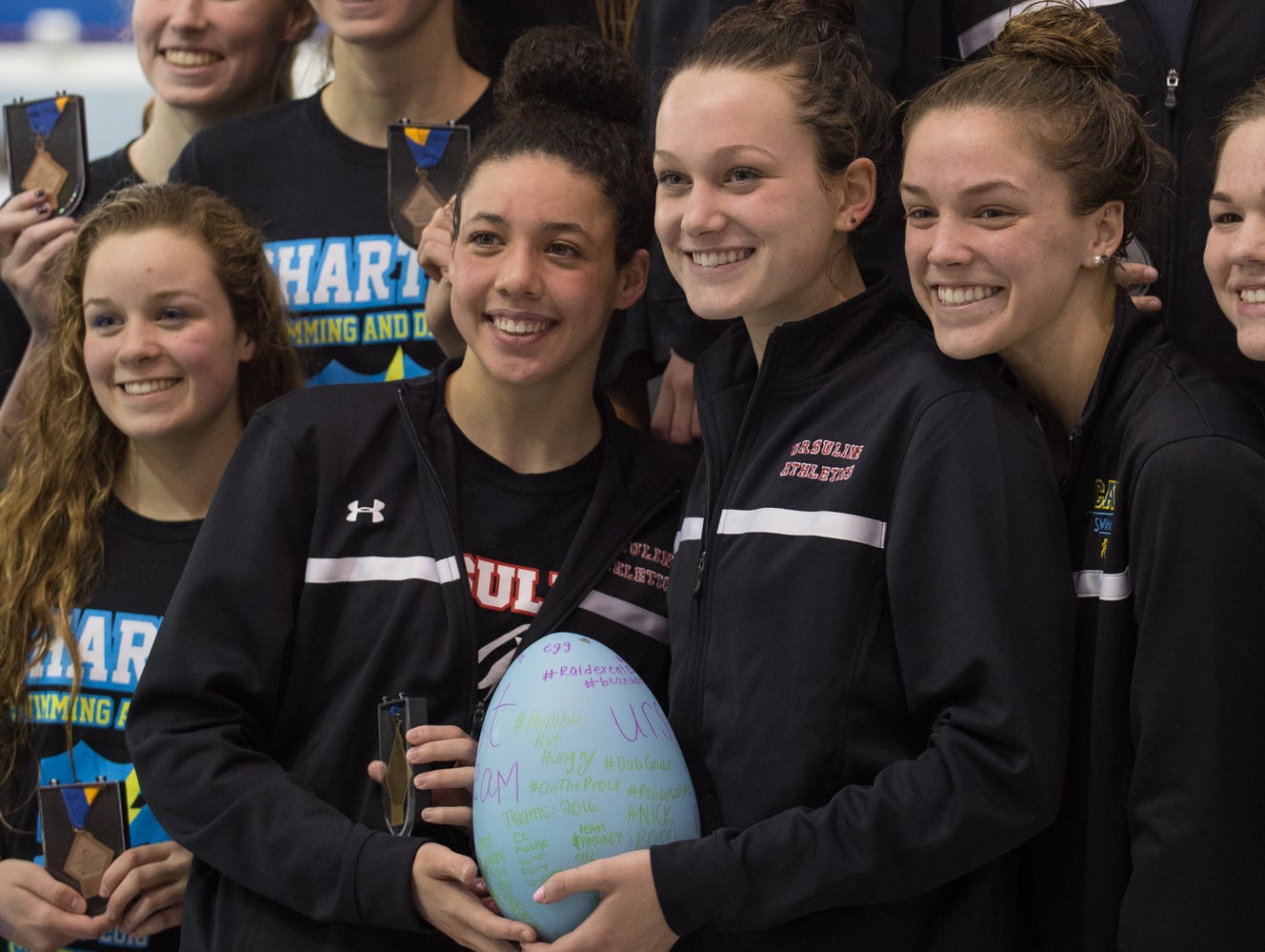 Swimmers from Ursuline Academy, center hold up their egg during the medal presentation for winning the 200 yard medley relay at the girl's DIAA swimming and diving championships at the University of Delaware.