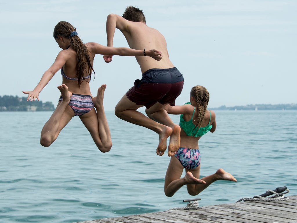 Children jump into the water at Lake Constance near Sipplingen, Germany.