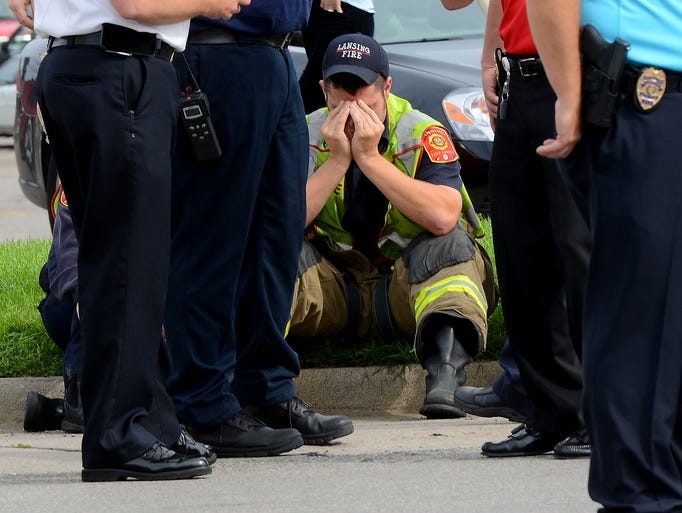 A Lansing firefighter puts his head in his hands while