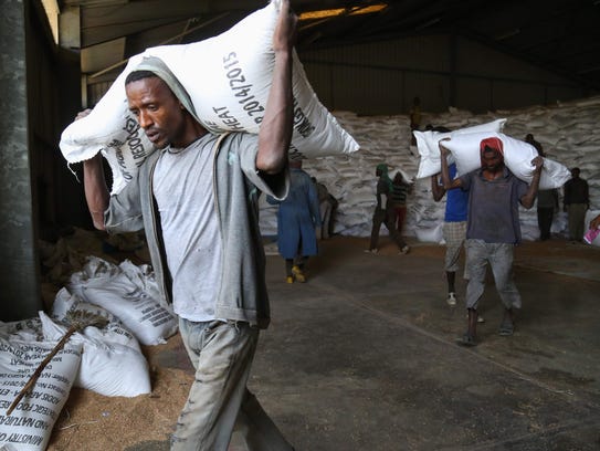 Workers move sacks of emergency food supplies in and
