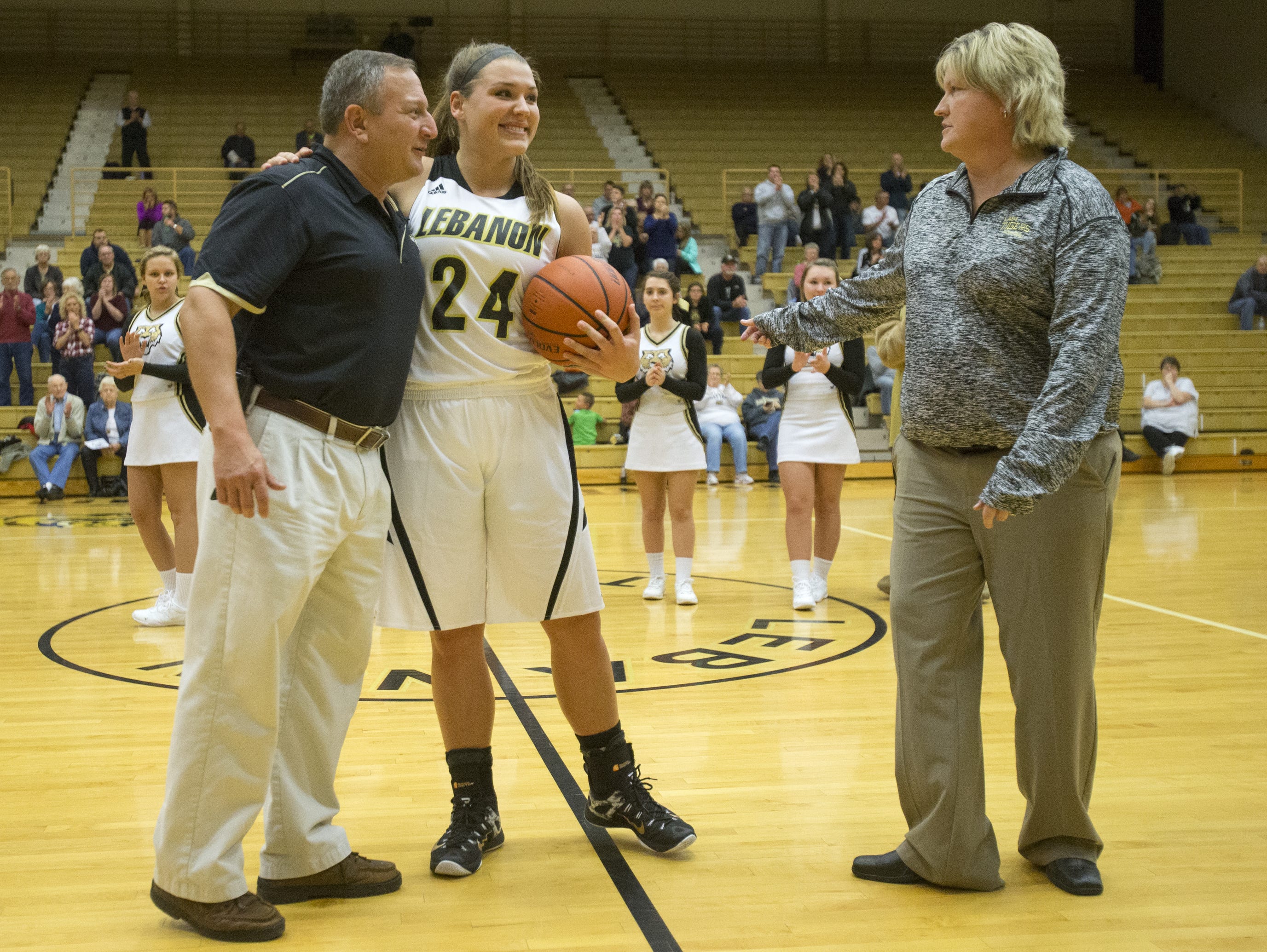 Kristen Spolyar is recognized by Lebanon AD Phil Levine (left) and coach Beth DeVinney after scoring her 2,000th point.