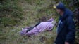 A rescuer walks past the body of a victim from the