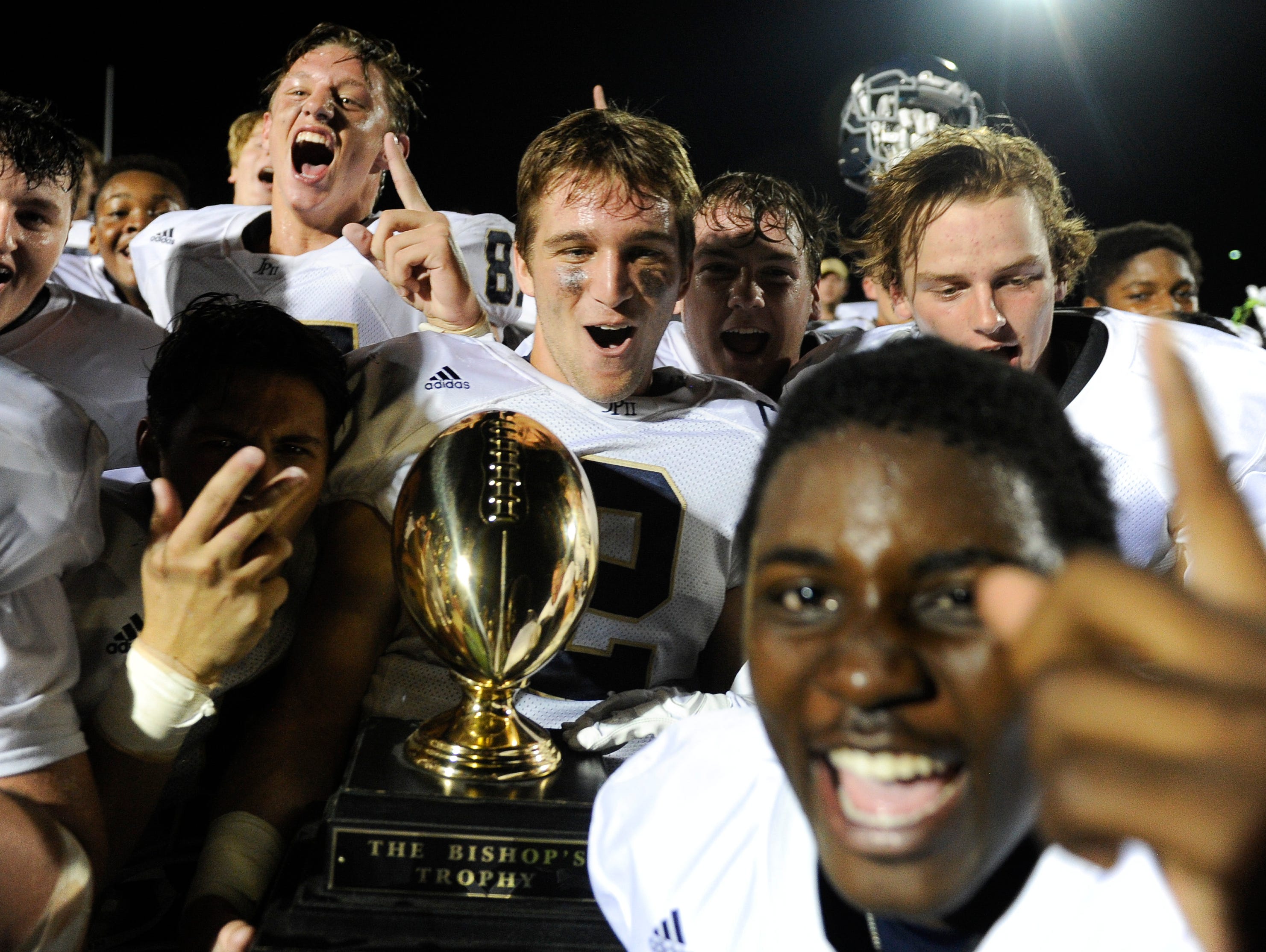 Members of the John Paul II football team celebrate their win over Father Ryan with the Bishop's trophy Friday Sept. 9, 2016, in Nashville, Tenn.