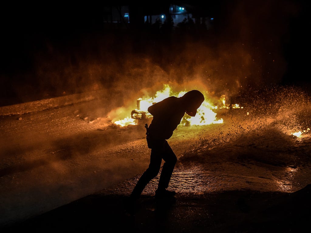A fire burns in the background as a militant dodges water from a water cannon during a demonstration in Istanbul's Gazi district  against the deadly attacks in Ankara. Anger towards President Recep Tayyip Erdogan over Turkey's worst-ever terrorist at