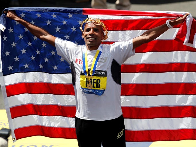 Meb Keflezighi holds up an American flag at the finish line after winning the Boston Marathon.