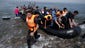 Syrians arrive aboard a dinghy from Turkey, on the
