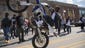 Motorcyclists perform wheelies near demonstrators in