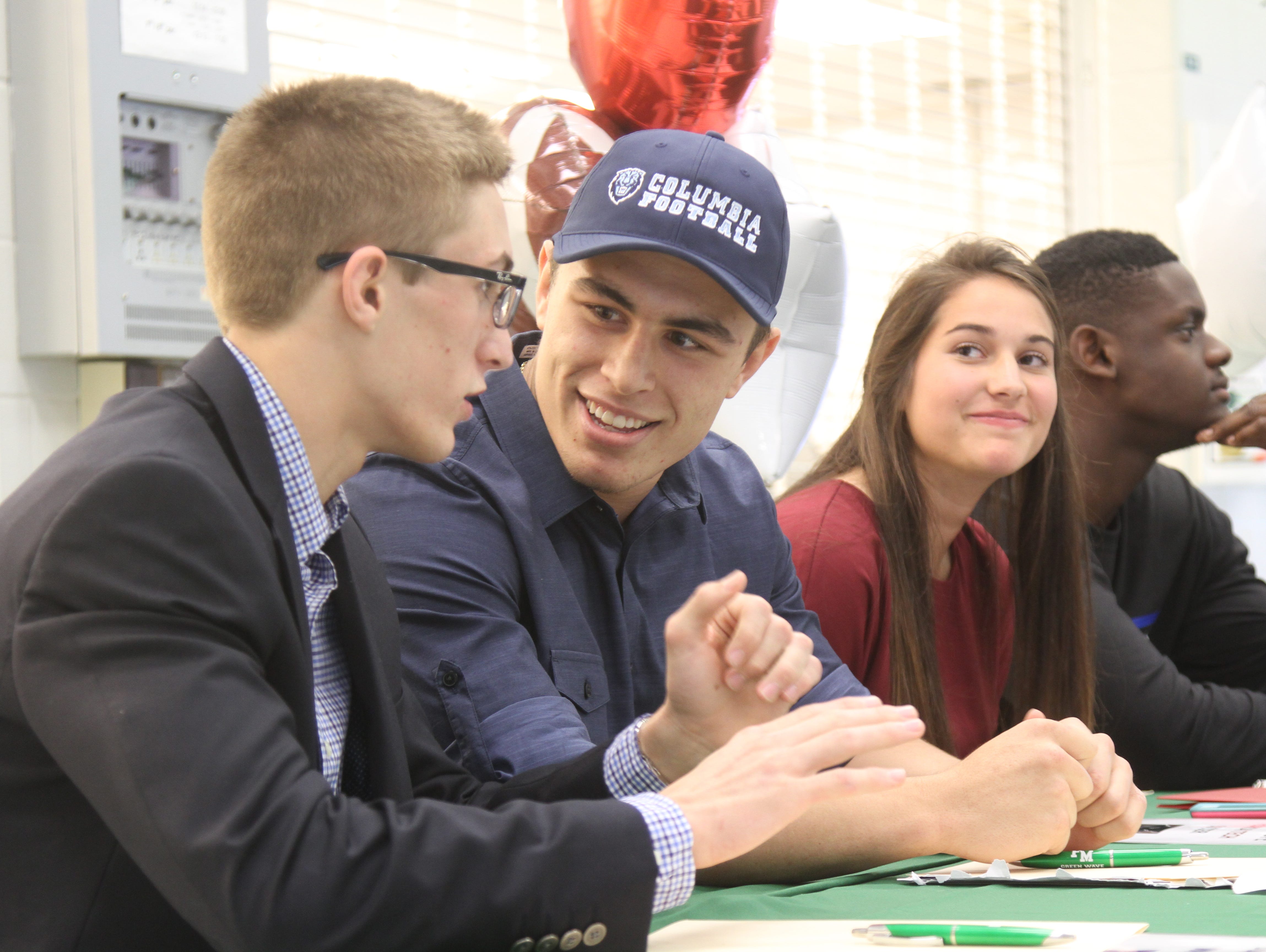 Colton Thomas, left, Levi McQuinn, Emily Swope, and Amos Corgelas, of Fort Myers High School prepare to sign their letters of intent during National Signing Day on Wednesday.