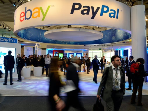 Attendees walk in front of an EBay and PayPal display