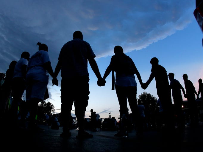 People pray after marching about a mile to the police station to protest the shooting of teenager Michael Brown in Ferguson, Mo. Brown's shooting on Aug. 9 by a Ferguson police officer has sparked more than week of protests, riots and looting in the St. Louis suburb.
