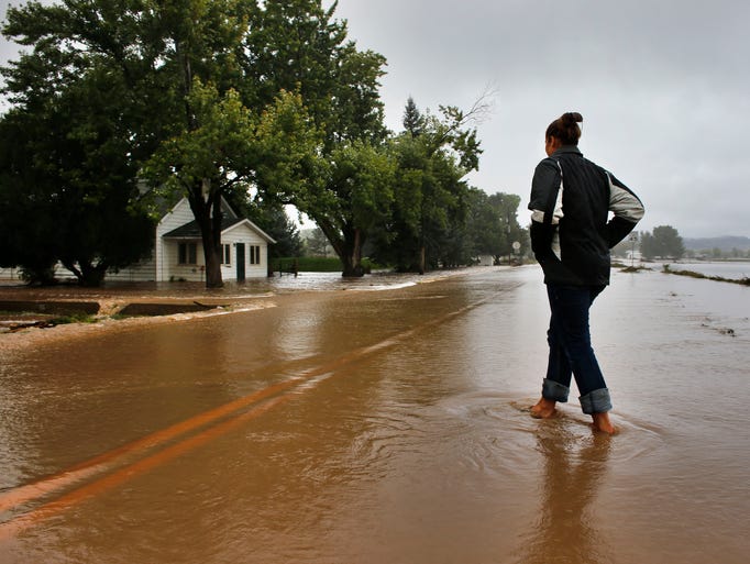 A woman walks in an evacuated neighborhood in Hygiene, Colo., where many homes are inundated with water from overflowing canals after days of flash floods and intense rain.