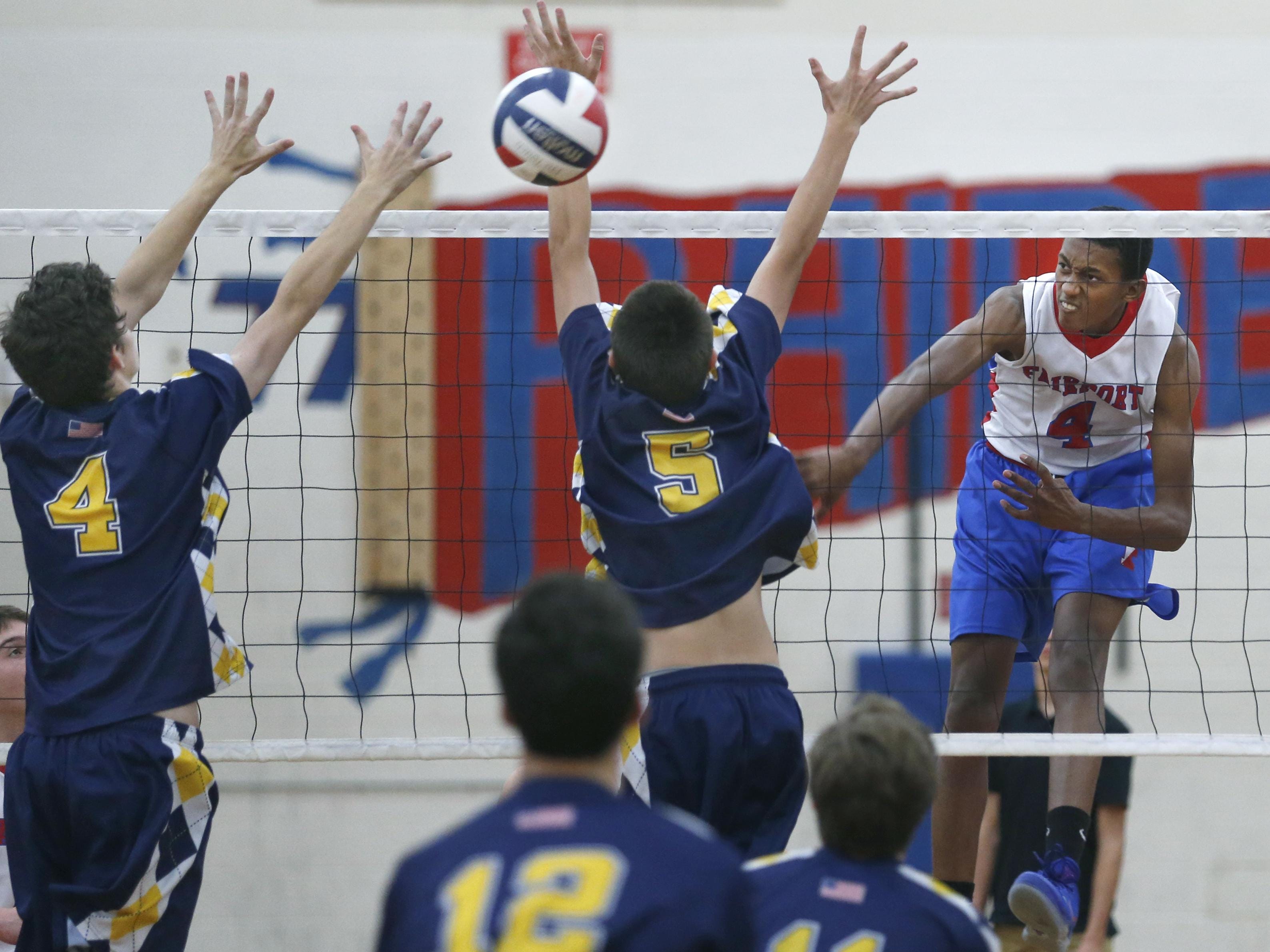 Fairport's Donovan Dey attacks against Victor's Hayden Hall and Cam Clark in the second set at Fairport High School. Fairport won in three sets.