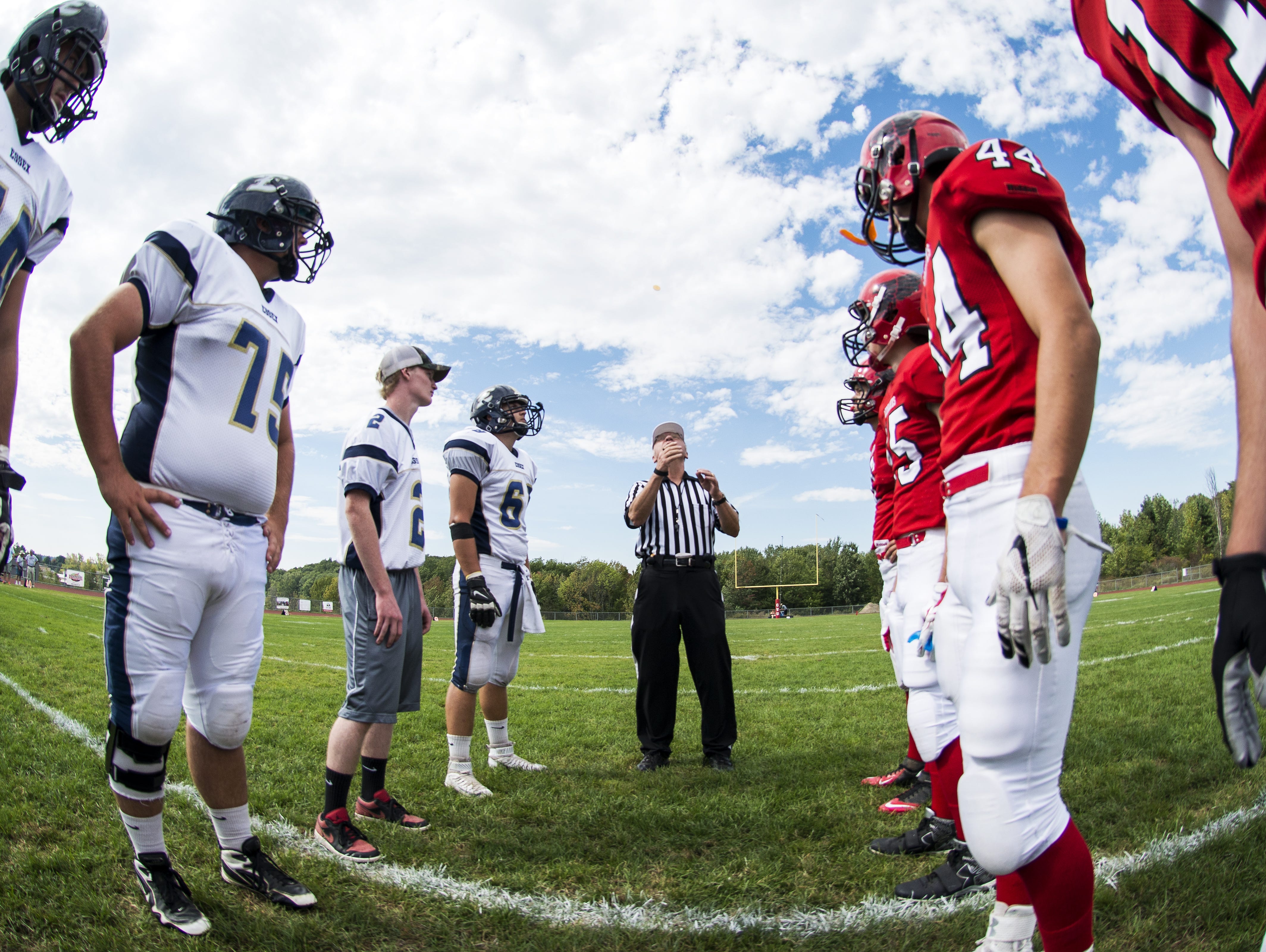 The referee fills a coin before the start of the high school football game between the Essex Hornets and the Champlain Valley Union Redhawks on Saturday afternoon.