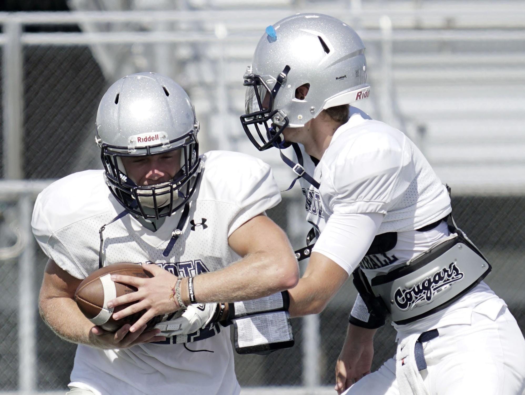 Quarterback Brett Droski, right, hands the ball to Kaiser Carleton during Macomb Dakota High School football practice on Wednesday, Aug. 17, 2016 at Macomb Dakota High School in Macomb Twp.