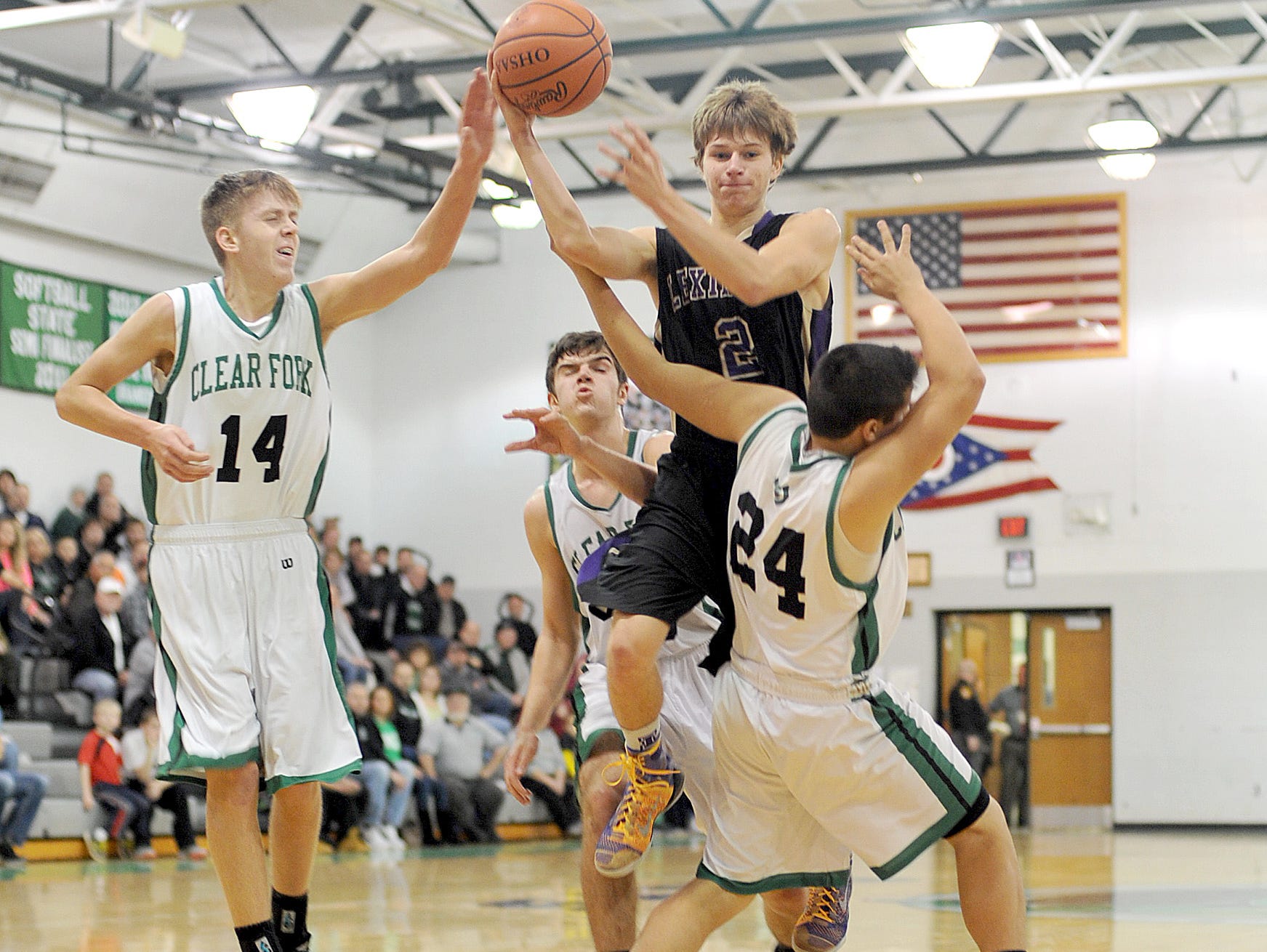 Lexington's Joey Zahn passes the ball as he is surrounded by Clear Fork's Chase Endicott, Chase Barrett and Daniel Spencer on Friday night at Clear Fork High School.