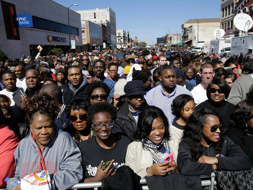A large crowd forms near a stage where President Barack