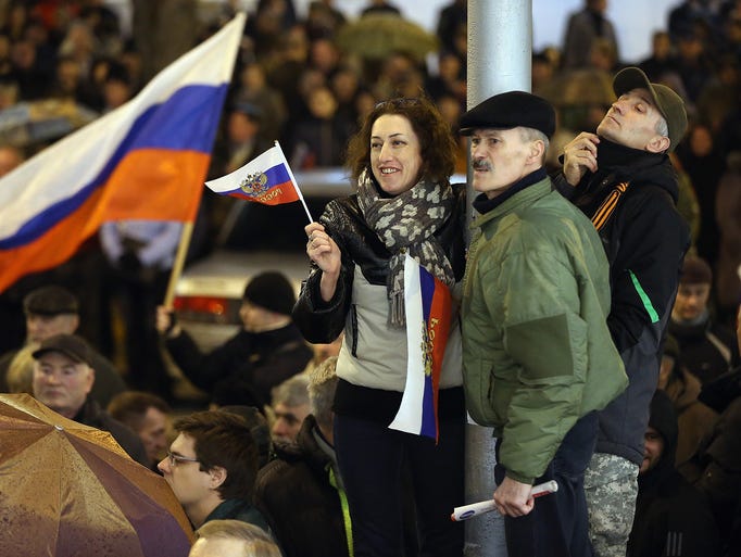 People wave Russian flags as they wait to hear the announcement that the Sevastopol regional council supported the vote for Crimea to secede from Ukraine and join Russia.