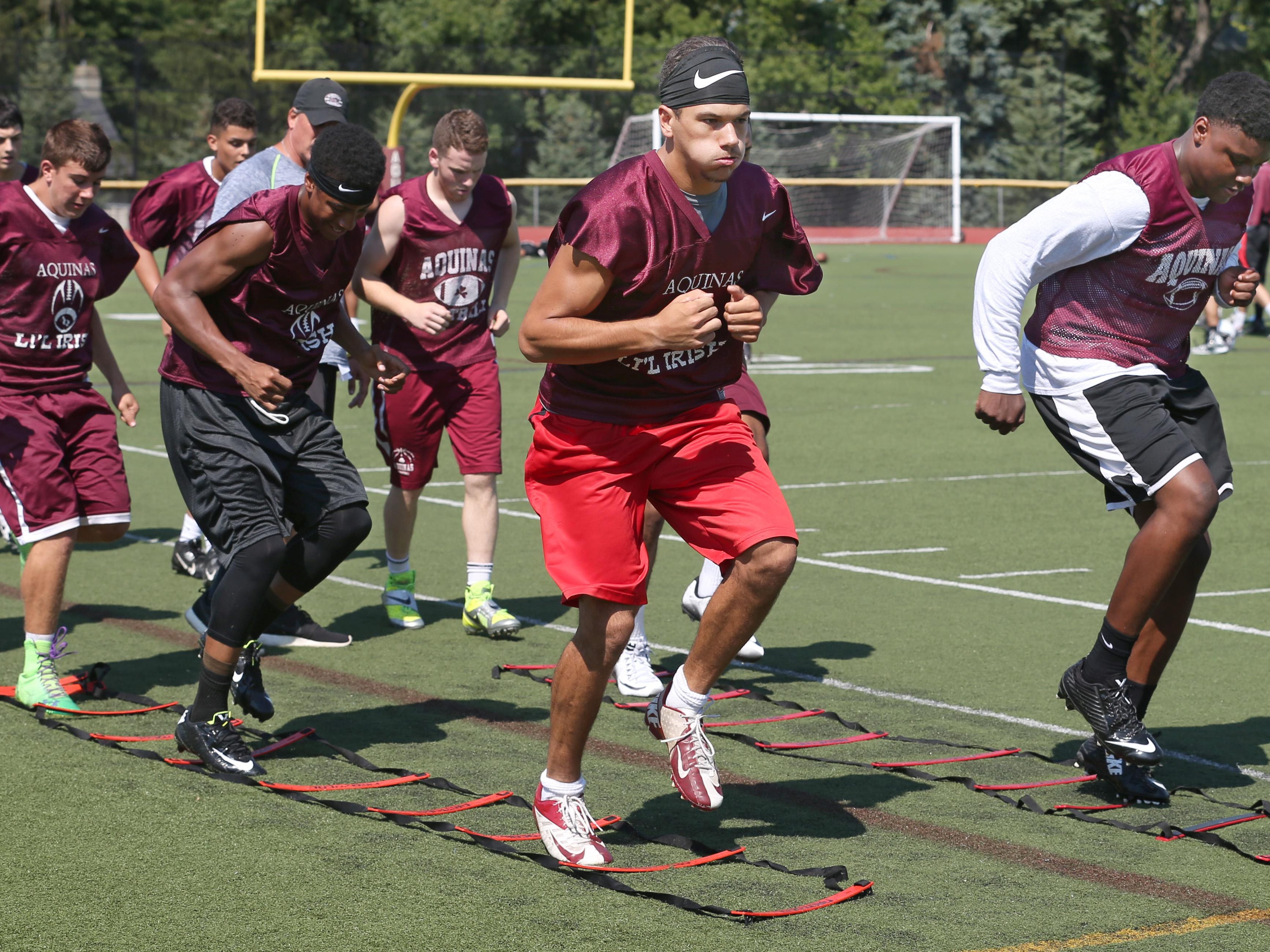 Aquinas QB Jake Zembiec and DE/LB Jamir Jones lead their teammates through the footwork agility drills on the opening day of high school football practices around Section V on Monday. Aquinas Institute is the first stop on the Democrat & Chronicle's high school football camp tour.