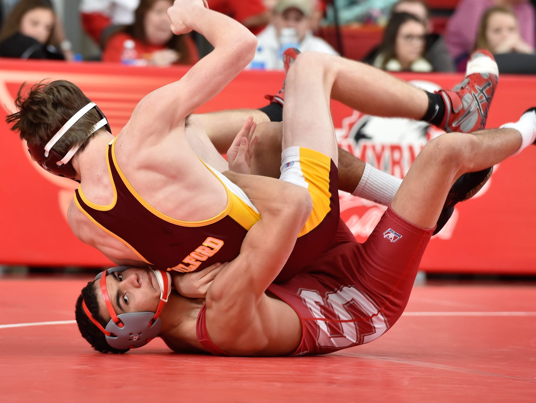 Smyrna's Nate Bryant rolls and brings Milford's Adam Funkhouser to the mat in the 138 pound match at Smyrna High School.