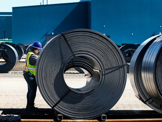 A workers inspects rolls of steel outside one of several