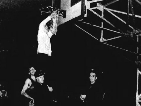 Frankfort student manager Leon Brower is photographed clipping the net at then-named Butler Fieldhouse as he was hoisted by an unidentified Indianapolis fireman.
