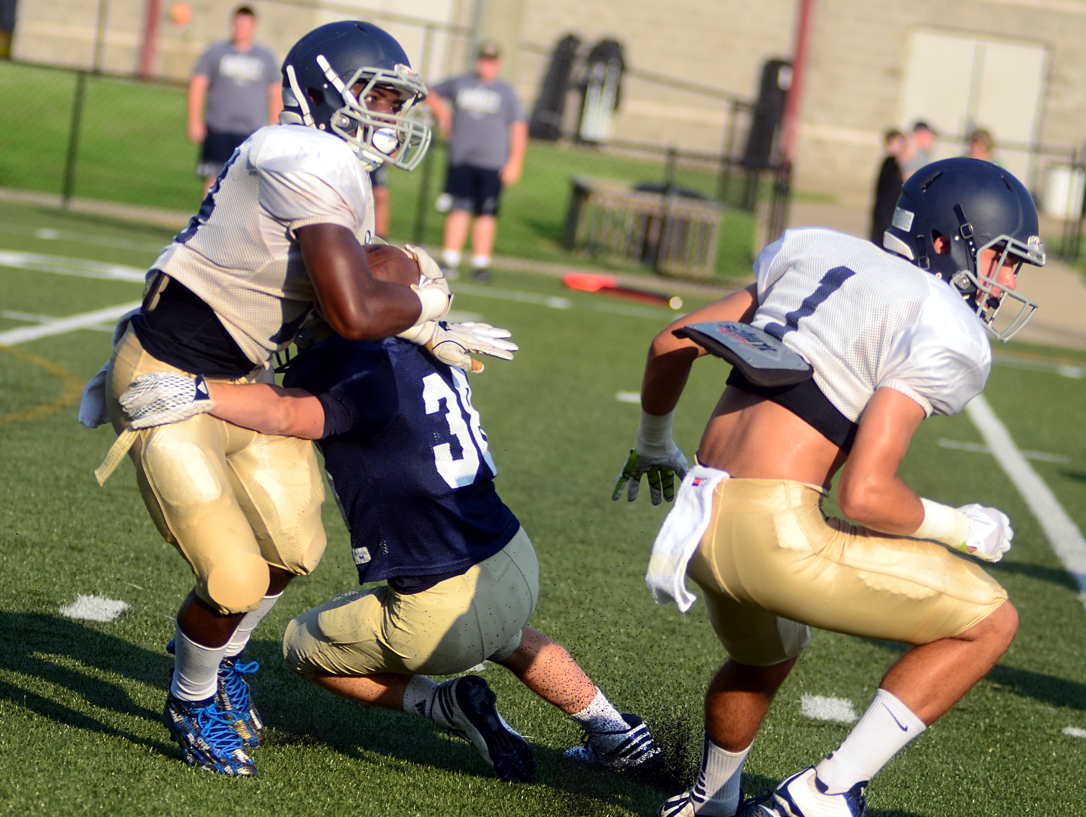 Pope John Paul II High senior C.J. Laws breaks a tackle as classmate Pace Dempsey (1) sets up a block during Friday's scrimmage against Sycamore.