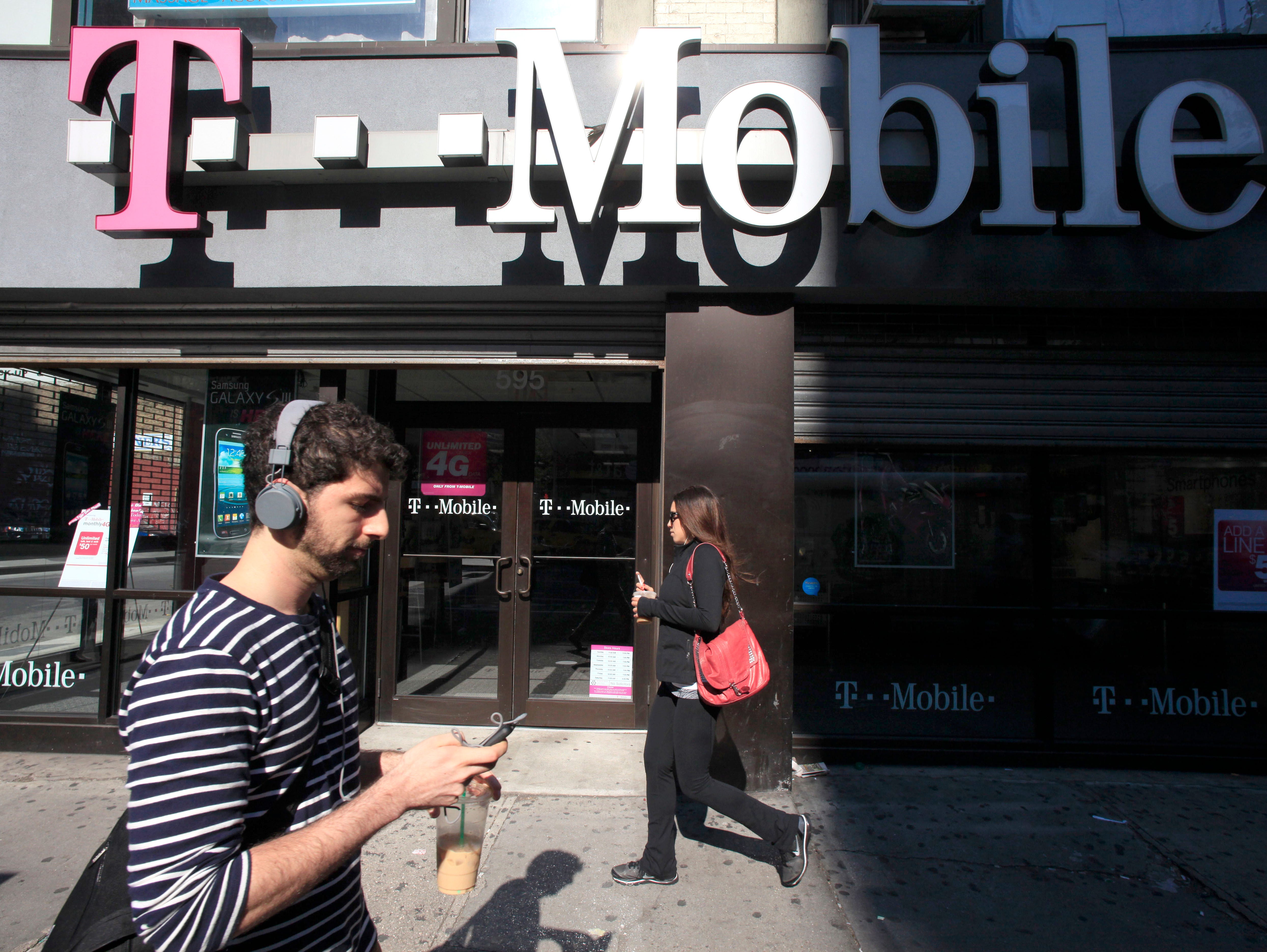In this Sept. 12, 2012 file photo, a man uses a cellphone as he passes a T-Mobile store in New York. Credit reporting agency Experian on Thursday, Oct. 1, 2015 said that hackers accessed the social security numbers, birthdates and other personal info