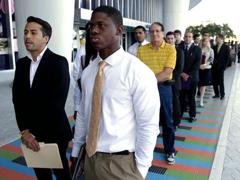 In this Oct. 23, 2013, file photo, Luis Mendez, 23, left, and Maurice Mike, 23, wait in line at a job fair held by the Miami Marlins, at Marlins Park in Miami.